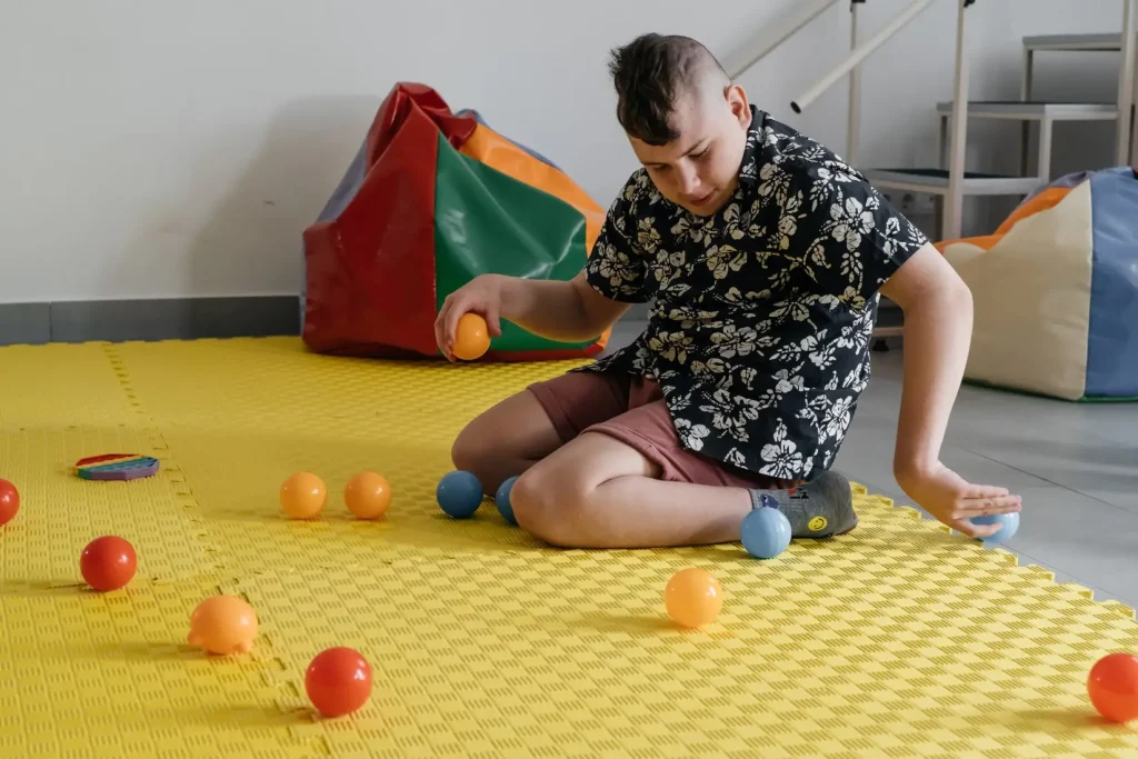 Disabled teenager playing with balls on mat